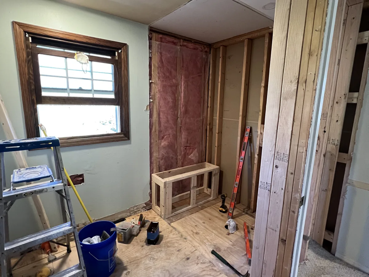 Bathroom stripped to the studs during demolition with exposed framing