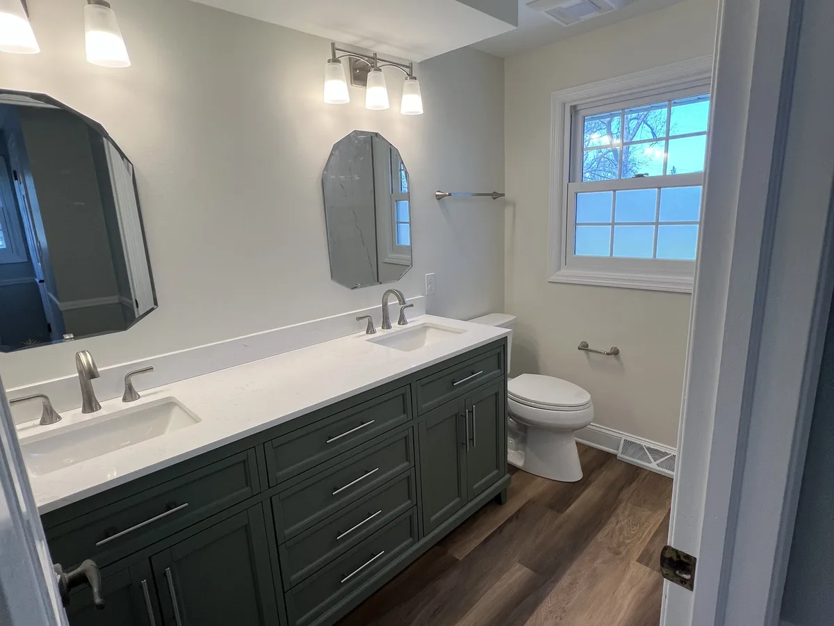 Remodeled bathroom with a double vanity, two arched mirrors and a bright window