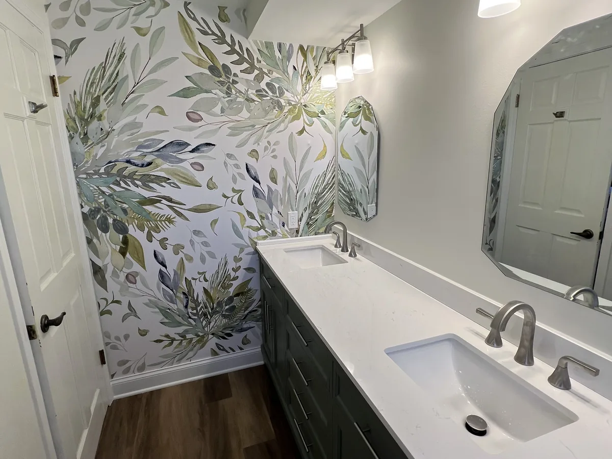 Finished bathroom vanity with a black counter and botanical wallpaper feature wall