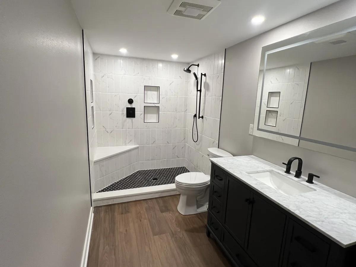 Remodeled bathroom with a dark vanity, quartz top and a curbless walk in shower