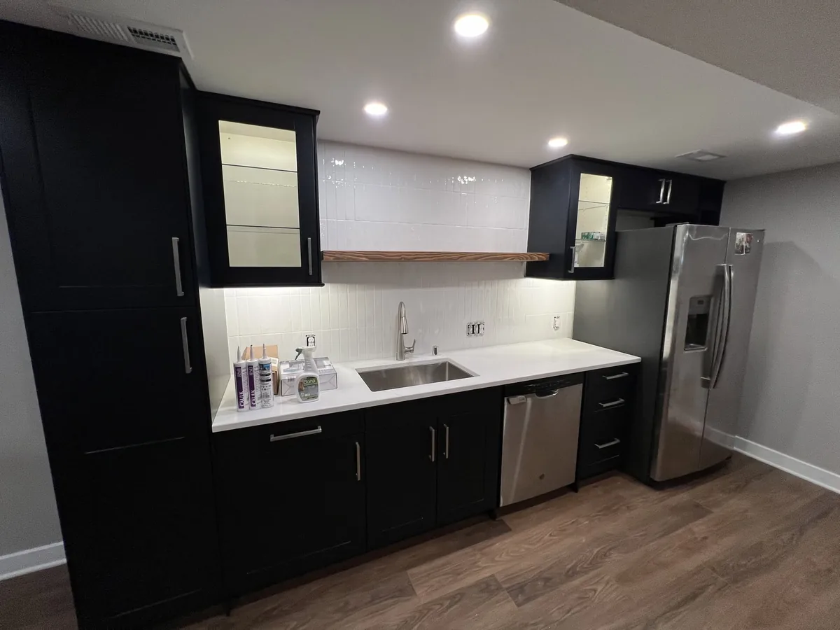 Remodeled kitchen with black cabinets, a light quartz counter and stainless appliances