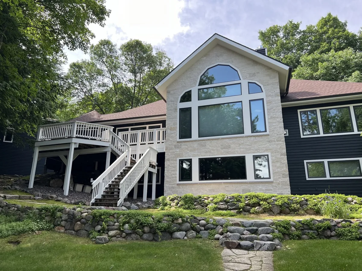 Lakefront home with light siding, white trim and an exterior staircase