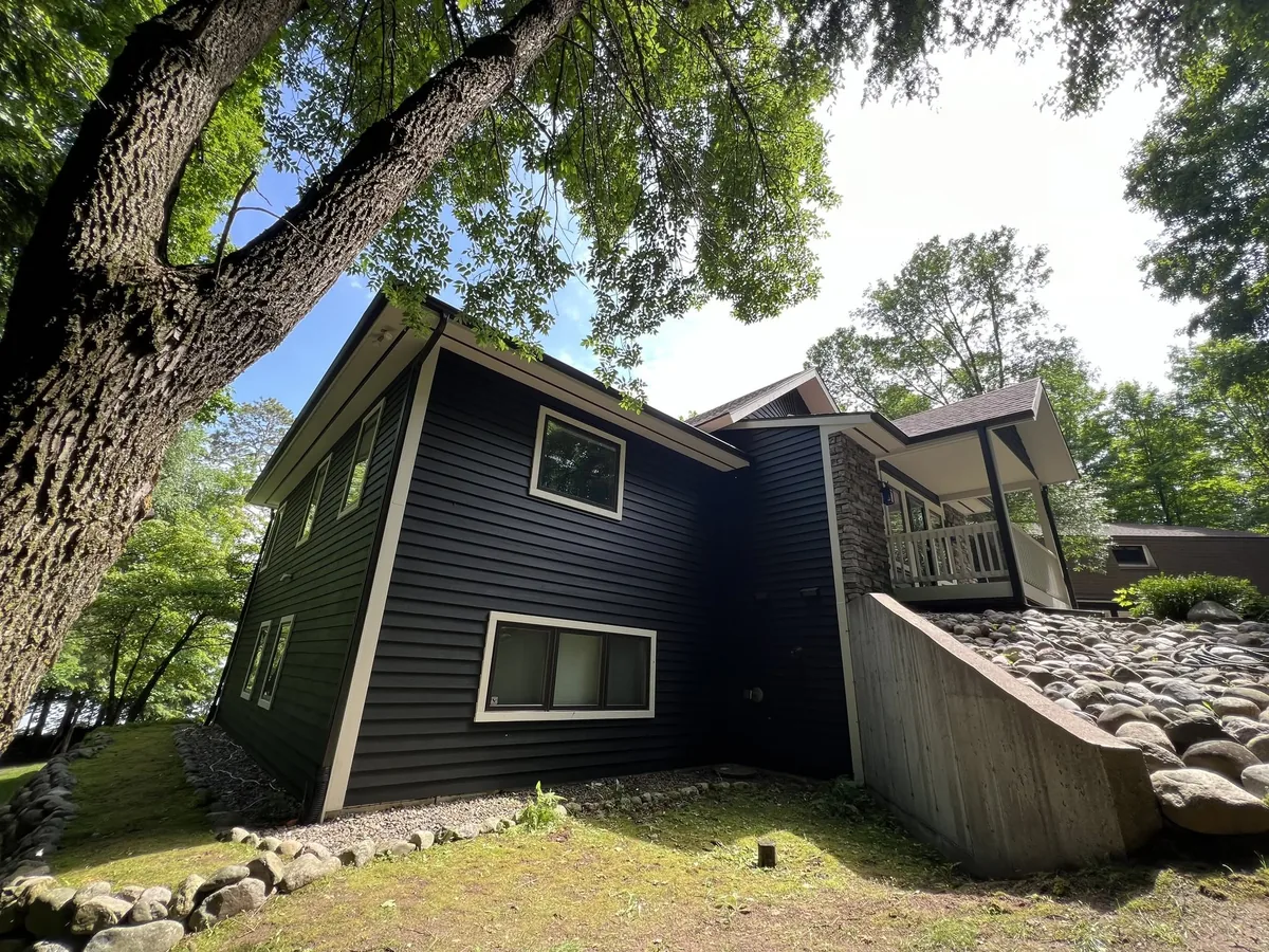Lakefront home finished in navy siding above a stone retaining wall in Waukesha County, Wisconsin