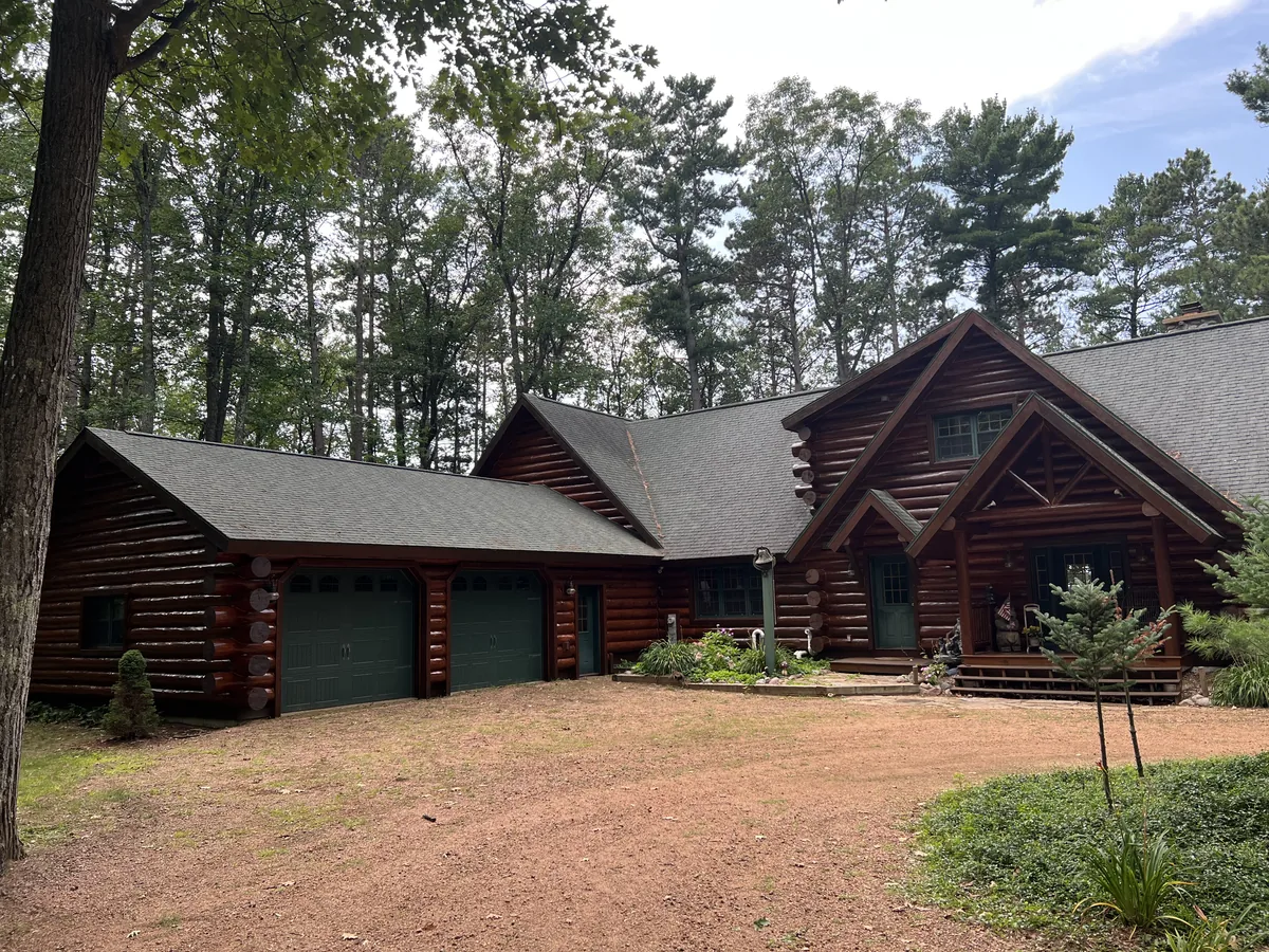 Log home exterior with an attached garage and gravel drive