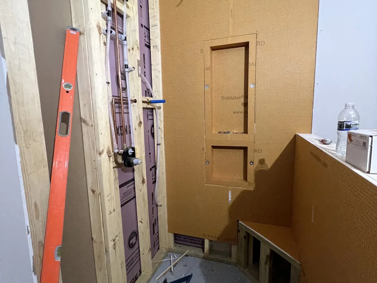 Shower under construction with framing, waterproofing board and a level in place