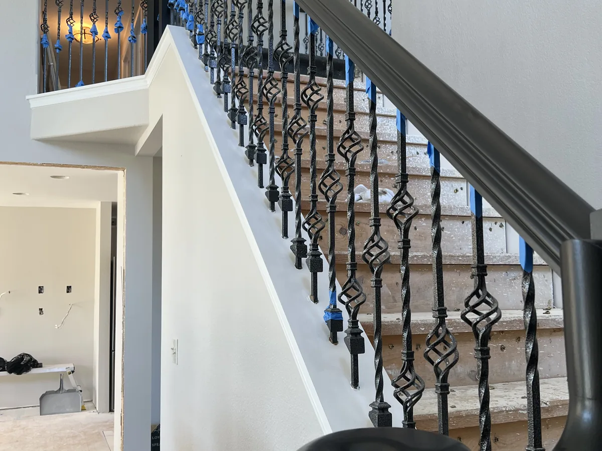 Finished staircase with decorative wrought iron balusters along the landing